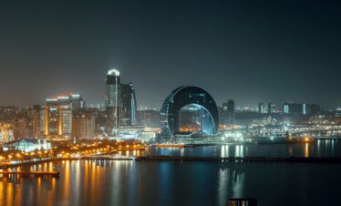 Baku night skyline with illuminated modern skyscrapers and the Caspian Eye Ferris wheel reflected in the Caspian Sea, Azerbaijan