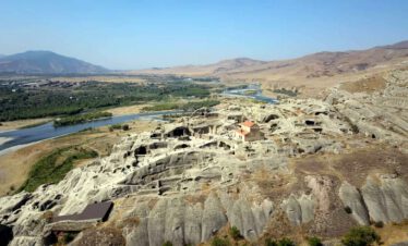 Aerial view of the ancient cave city of Uplistsikhe carved into sandstone rock above the meandering Kura River, Georgia