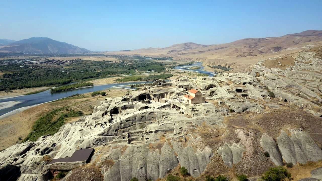 Aerial view of the ancient cave city of Uplistsikhe carved into sandstone rock above the meandering Kura River, Georgia